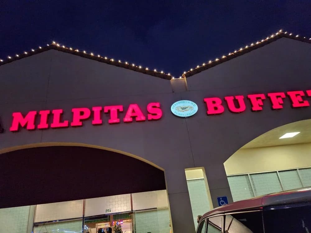 The lit red Milpitas Buffet sign above the entrance after dark