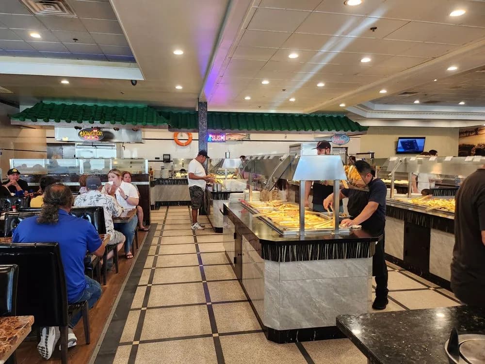 Buffet stations with staff refilling trays while diners eat at nearby tables