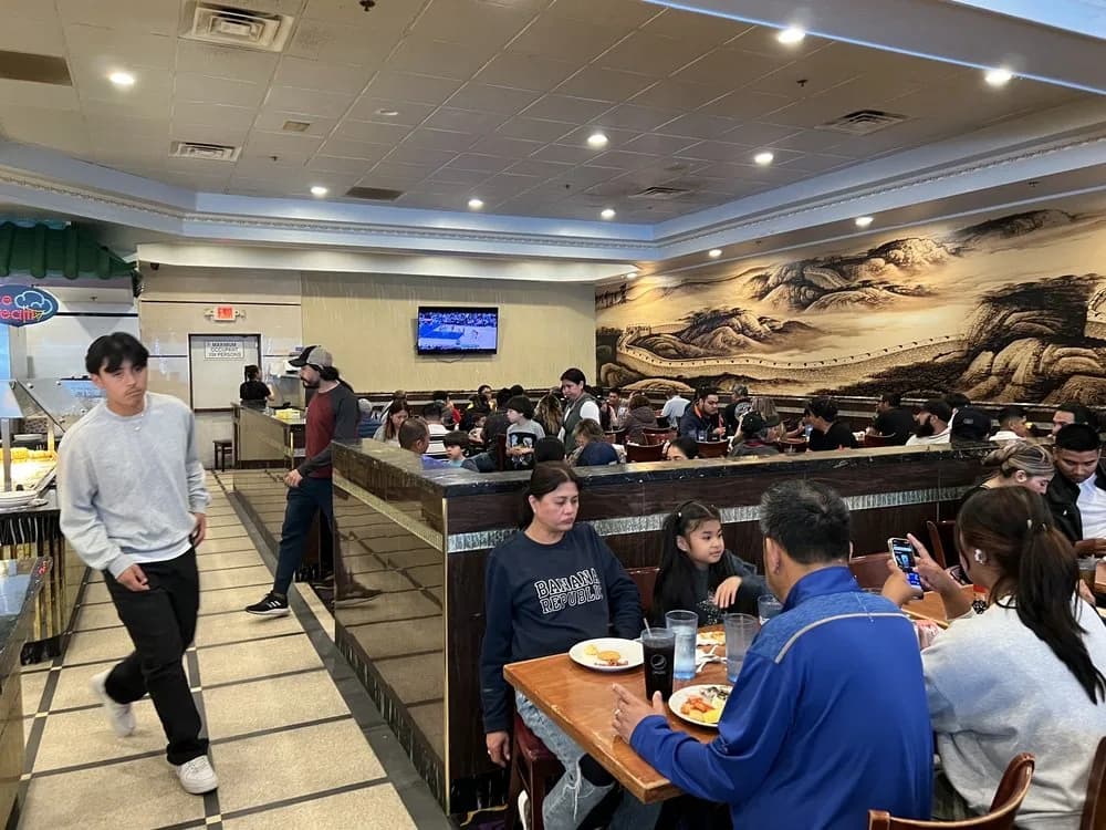 Families eating in the dining room beneath a painted Great Wall mural