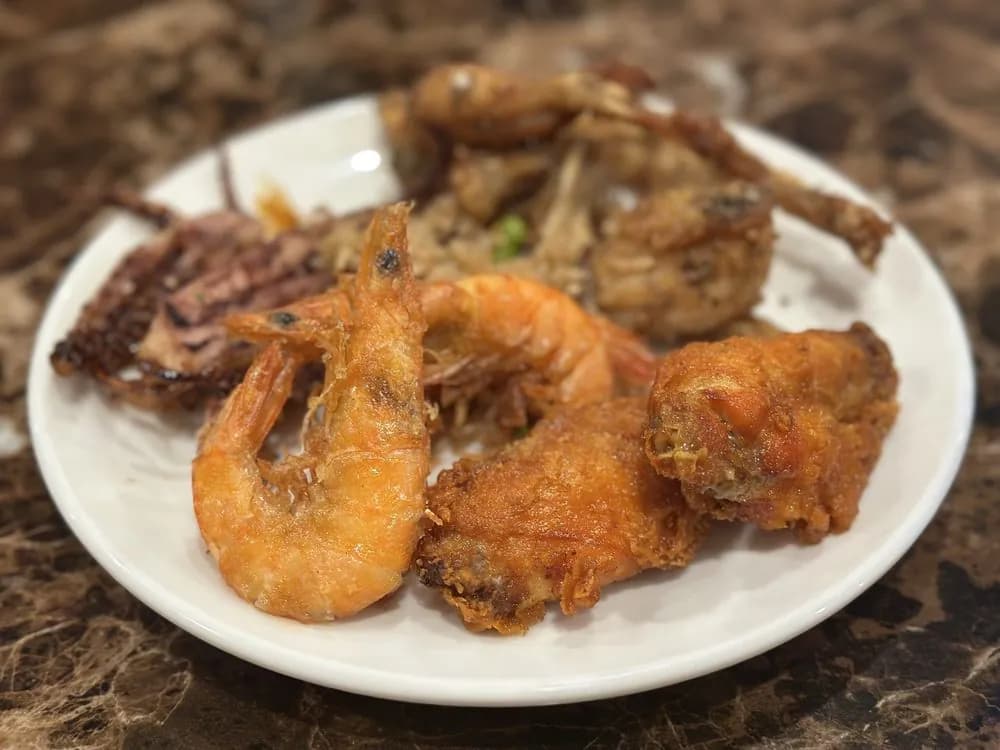 A buffet plate with shell-on fried shrimp, fried squid and fried chicken